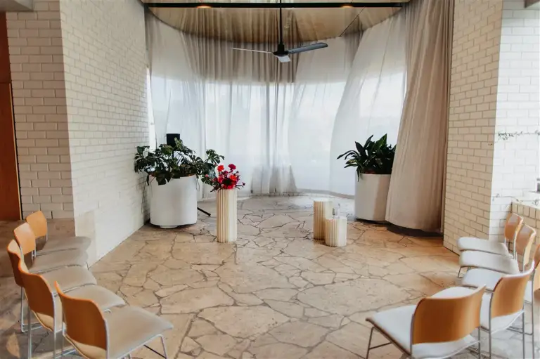 Amy's Bo & Luca gown catches the light as she prepares in The Calile's terrace space, with elegant minimalist florals by Lilac Green in the foreground
