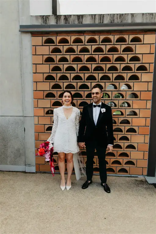 The couple embracing in the rain as dusk falls over Brisbane, with The Calile's distinctive lighting creating a cinematic atmosphere